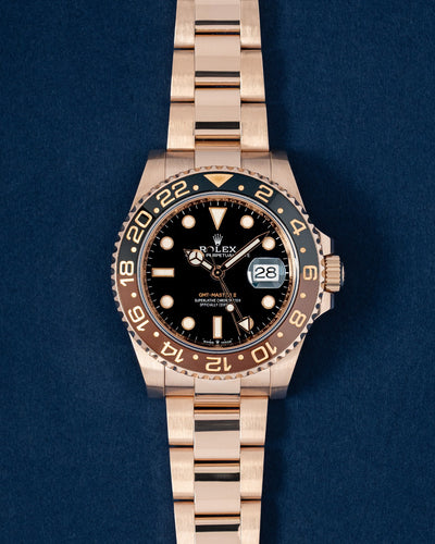 A preowned 2021 Rolex GMT-Master II reference 126715CHNR displaying its solid 18k Everose gold case, black dial, and iconic brown and black Cerachrom Root Beer bezel at Grand Caliber in Dallas