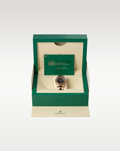 The complete retail collector package featuring the pre-owned 18k Everose gold GMT watch resting securely inside its inner green wave-motif presentation display chest