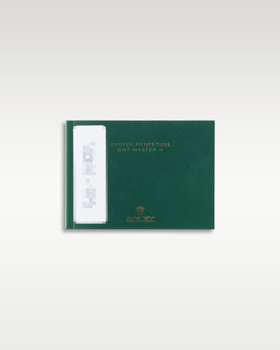 The official green Rolex GMT-Master II user operating manual and worldwide warranty booklet laid flat on a light background