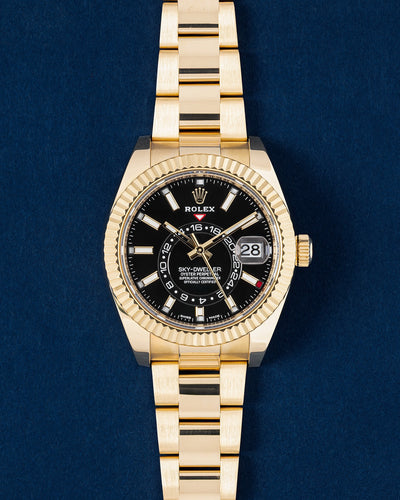 18k yellow gold Rolex Sky-Dweller watch featuring a black dial, off-center rotating 24-hour disc, fluted Ring Command bezel and an Oyster bracelet