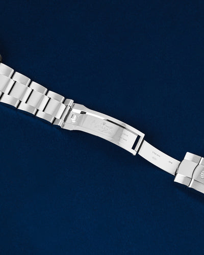 flat top-down view of the internal folding clasp blades and the micro-adjusting Easylink comfort extension system of a steel Rolex open over a navy background