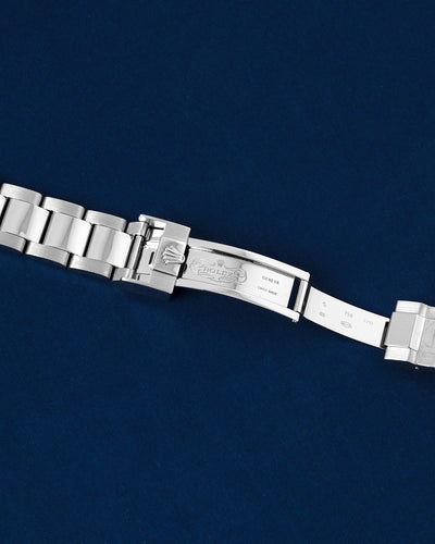 flat top-down view of the internal folding clasp blades and the micro-adjusting Glidelock diving extension system of a white gold Rolex open over a navy background