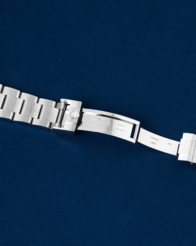 flat top-down view of the internal folding clasp blades and the micro-adjusting Glidelock diving extension system of a steel Rolex open over a navy background