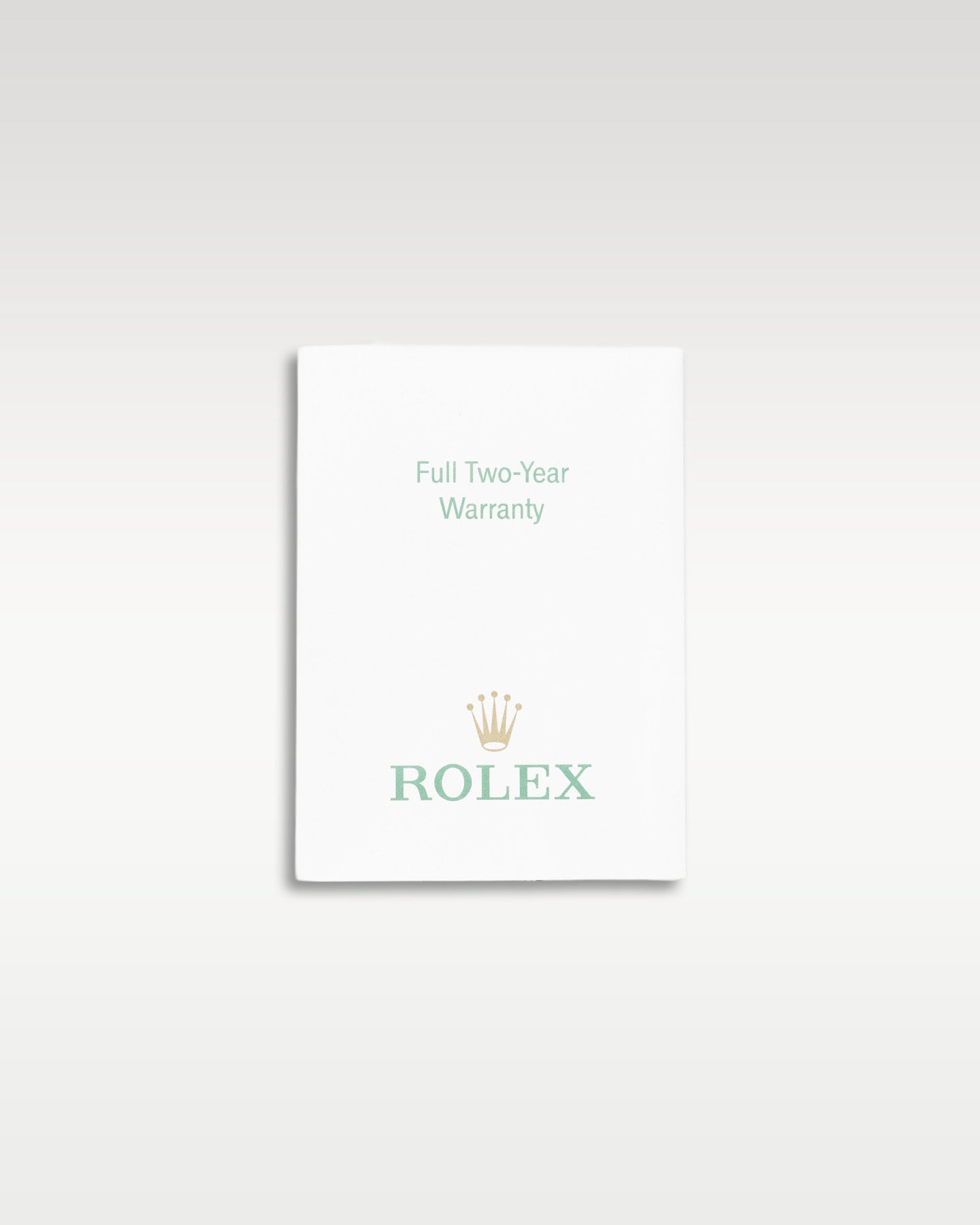 small white paper Rolex factory translation booklet displayed flat against a neutral light studio backdrop