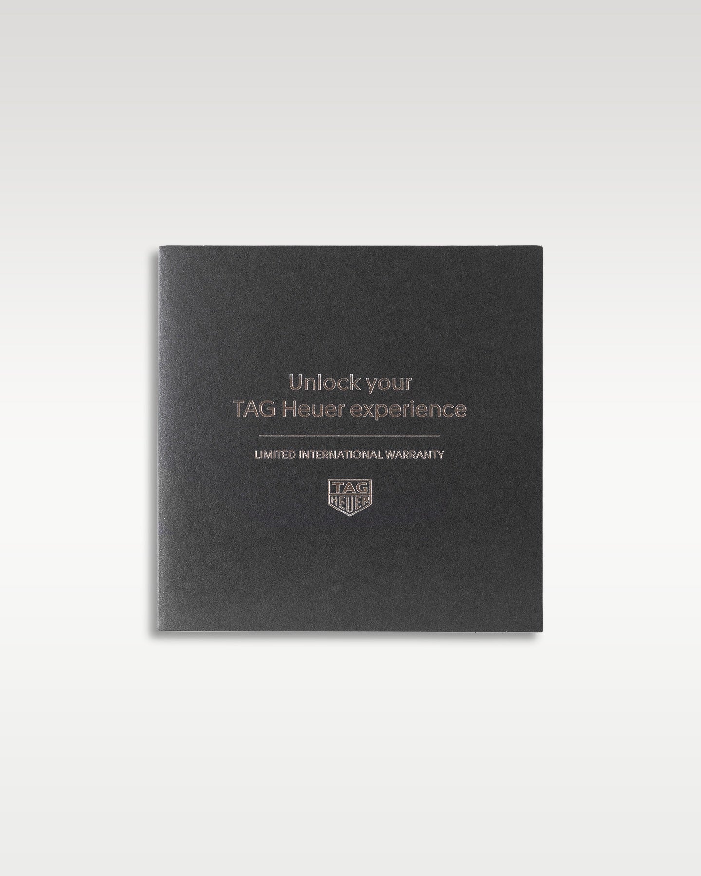 dark grey textured TAG Heuer customer experience welcome guide and ownership booklet resting flat in a studio presentation
