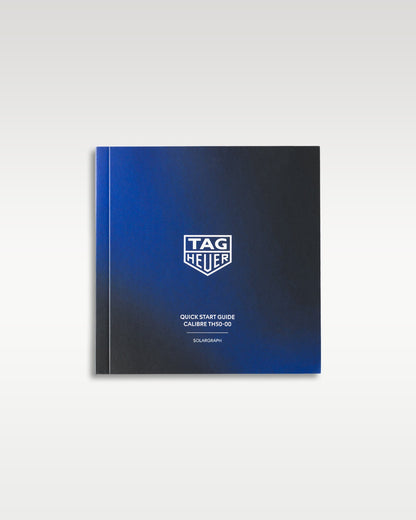 front cover of the black and blue gradient TAG Heuer user manual and technical operating instructions booklet displayed flat on a white studio backdrop