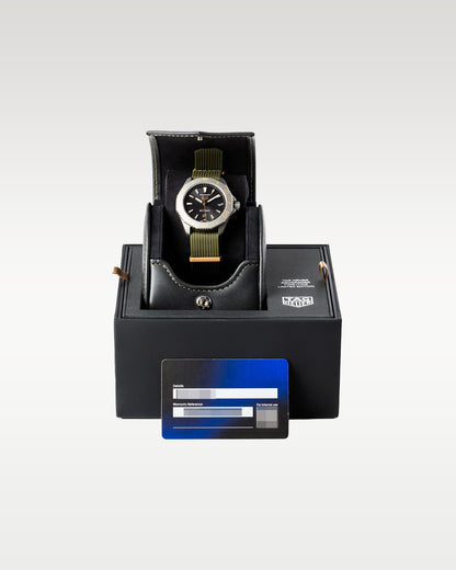 titanium TAG Heuer Aquaracer Solargraph Sundowner watch displayed upright on its cushion inside its open signature black luxury presentation box with the warranty card