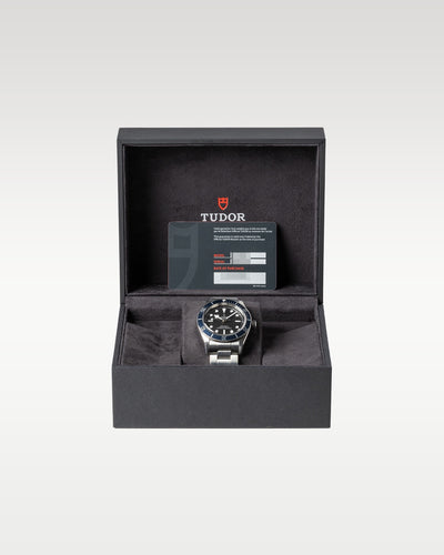 open black textured Tudor presentation box displaying a blue bezel Black Bay 41 automatic diver watch on a watch pillow