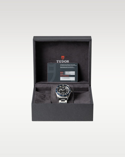 open black textured Tudor presentation box displaying a blue bezel Black Bay 41 automatic diver watch on a watch pillow