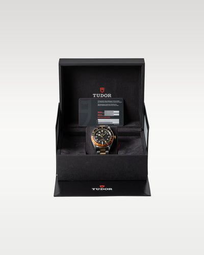 open black textured Tudor presentation box housing a two-tone Black Bay GMT Root Beer watch inside