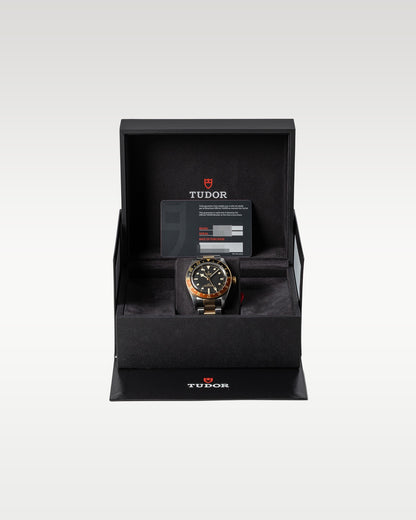 open black textured Tudor presentation box housing a two-tone Black Bay GMT Root Beer watch inside