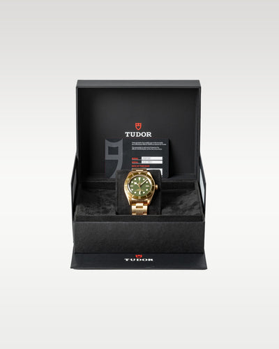 The complete retail presentation package of an unworn solid 18k gold Tudor Black Bay 58 timepiece resting securely within its inner textured black watch chest