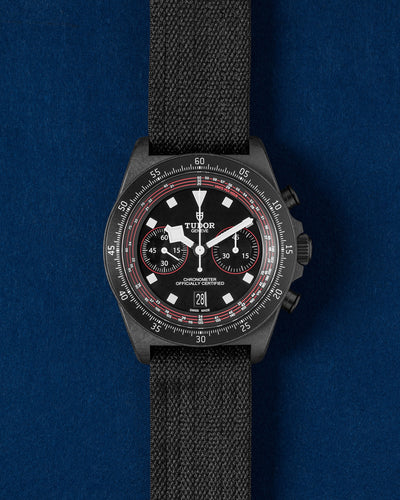 Tudor Pelagos FXD Chrono Cycling Edition watch featuring a matte black carbon composite case, red dial accents and a single-piece black fabric strap