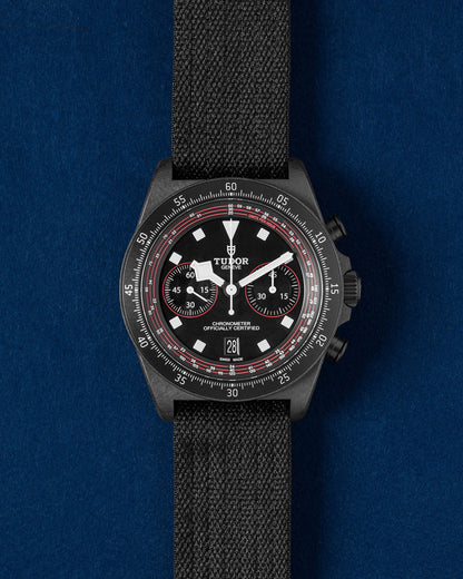 Tudor Pelagos FXD Chrono Cycling Edition watch featuring a matte black carbon composite case, red dial accents and a single-piece black fabric strap