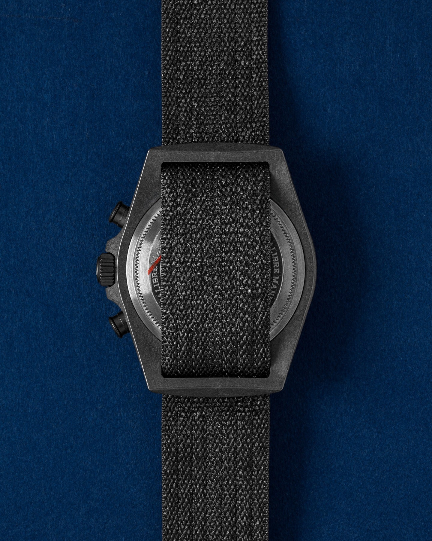 solid caseback view of a Tudor Pelagos FXD Chronograph showing the single-piece fabric strap threading through the fixed lugs