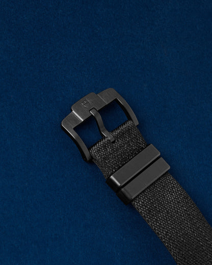 black fabric hook-and-loop strap with a matte black titanium Ti ti-buckle closure on a Tudor Pelagos FXD watch