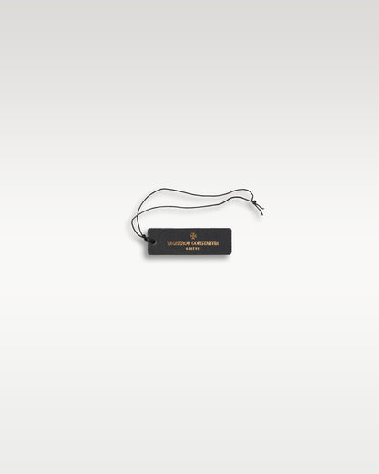 official rectangular black plastic Vacheron Constantin Geneve watch string hangtag resting on a light grey backdrop
