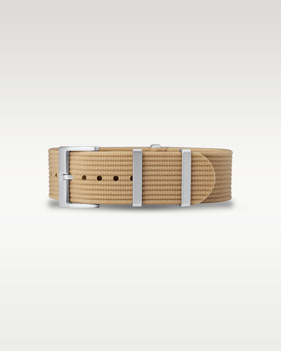 Flat layout view of a desert tan woven nylon watch strap folded with brushed silver hardware
