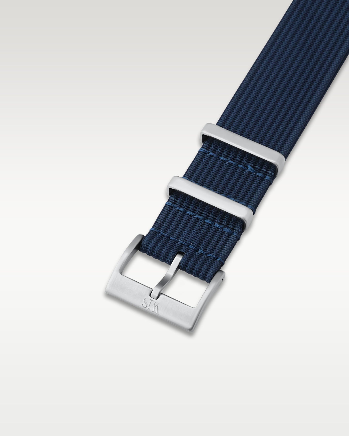 Angled detail shot of a rich navy marine blue nylon watch band showing its pre-installed brushed silver pin buckle