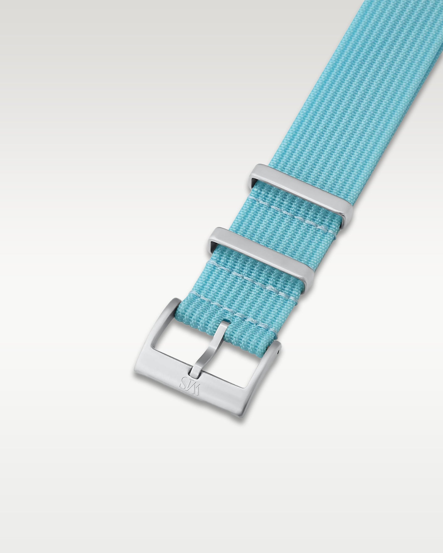 Angled detail shot of an aquatic Miami blue nylon watch band showing its pre-installed brushed silver pin buckle