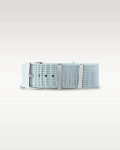 Flat layout view of a muted sage green woven nylon watch strap folded with brushed silver hardware