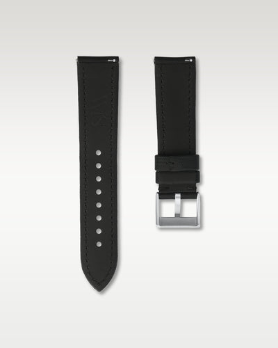 Reverse side of a 22mm black sailcloth watch strap showing integrated quick-release spring levers, dark lining, and engraved buckle