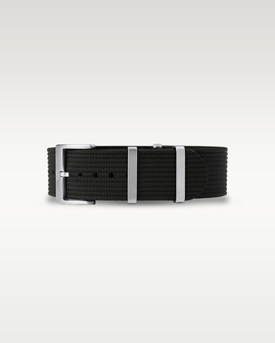 Flat layout view of a pitch black woven nylon watch strap folded with brushed steel hardware