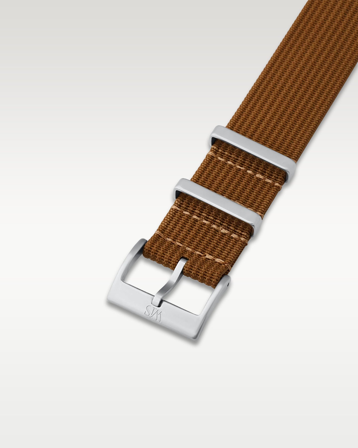 Angled detail shot of a rich woodland brown nylon watch band showing its pre-installed brushed silver pin buckle